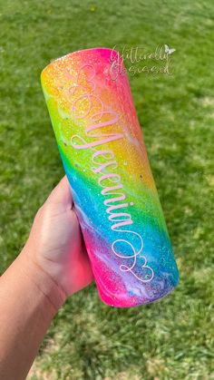 someone holding up a rainbow colored tumbler in their hand