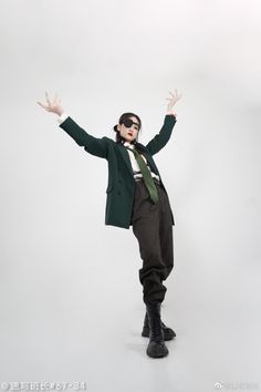 a man in a green jacket and tie with his arms spread out, posing for the camera