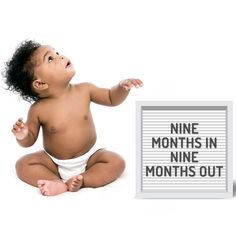 a baby sitting next to a sign that says nine months in nine months out