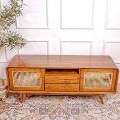 an old fashioned wooden tv stand with two drawers and wicker inserts on the sides