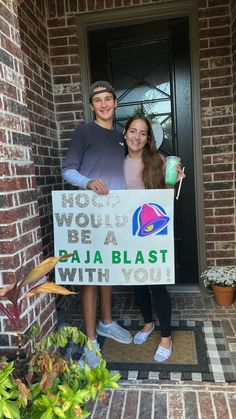 two people standing in front of a door holding a sign