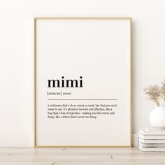 a white framed poster with the words mimi on it next to a stack of books