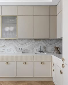 a kitchen with white cabinets and marble counter tops, along with wooden flooring that matches the walls