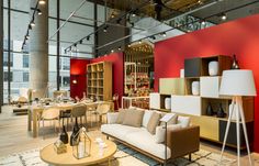 a living room filled with furniture next to a tall red wall and lots of windows