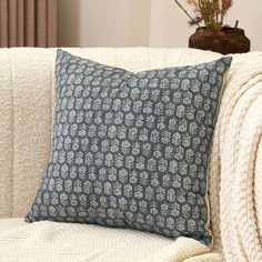 a blue and white pillow sitting on top of a couch