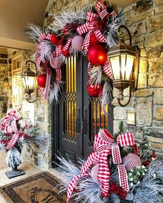 a christmas wreath with red and white ornaments on it next to a black front door