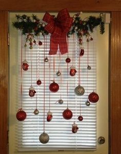 christmas decorations hanging on the window sill with red bows and baubles attached to it