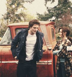 two people standing in front of an old truck