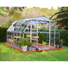 a small greenhouse with plants growing inside and on the ground next to potted plants