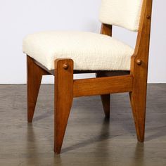 a wooden chair with white upholstered seat and back cushion on top of wood flooring