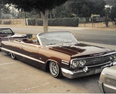 an old car parked on the side of the road next to other cars in a parking lot