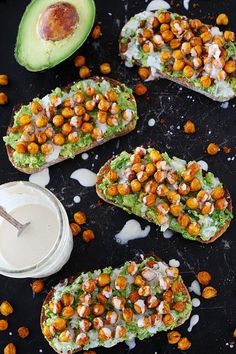 avocado toast with chickpeas and ranch dressing on a black surface next to an avocado