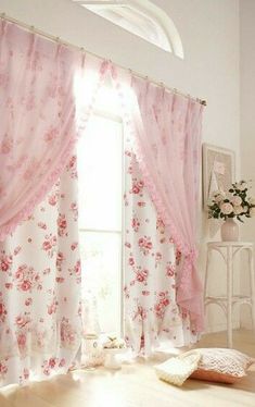 a room with a window covered in pink curtains and flowers on the drapes