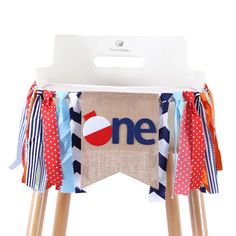 a wooden stool with a one sign on it's side and red, white, and blue ribbons around the legs