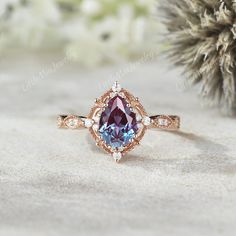 a pink and blue ring sitting on top of a white table next to a pine tree