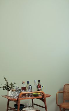 two chairs and a table with drinks on it in front of a wall painted green