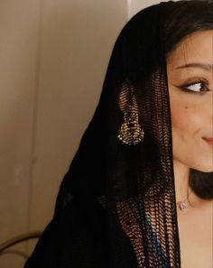 a close up of a woman wearing a black veil and diamond earring on her head