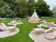 the lawn is decorated with pink and white pillows, chairs, and a teepee tent