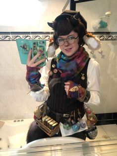 a woman in costume standing next to a bathroom sink holding up her peace sign with both hands