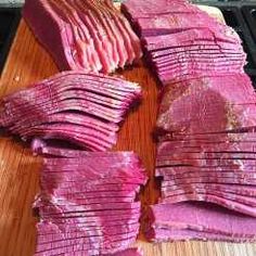 sliced up meat sitting on top of a wooden cutting board