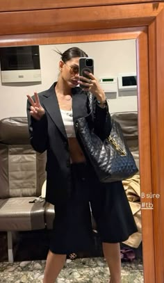 a woman taking a selfie in front of a mirror with her handbag and purse