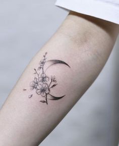 a woman's arm with a flower and crescent tattoo on the left side of her arm