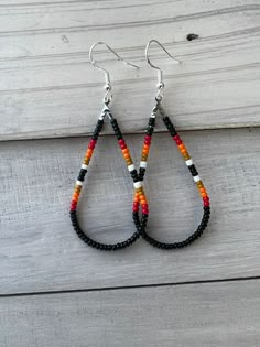 the beaded tear shaped earrings are made from black, orange and white seed beads