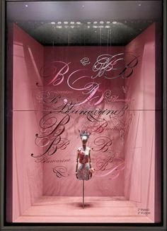 a pink display case with a mannequin in the center and writing on it