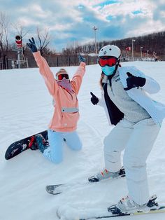 two snowboarders pose in the snow with their hands up and one person on skis