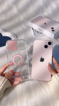 a person holding an iphone in their hand next to two other cases on a bed