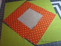 an orange and green patchwork quilt on a cutting board