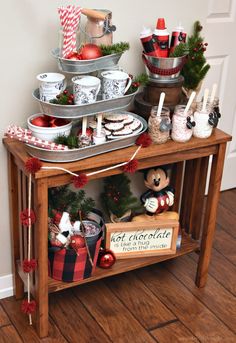 a wooden table topped with lots of christmas decorations next to a large clock on the wall