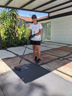 a woman is cleaning the driveway with a mop and duster in her hand