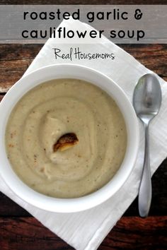 a white bowl filled with soup sitting on top of a napkin next to a spoon