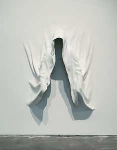 an abstract sculpture is shown in the middle of a room with white walls and black flooring