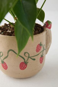 a potted plant with strawberries painted on it's side and green leaves