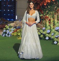 a woman in a white dress standing on the green grass with blue flowers behind her