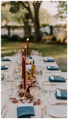 a long table set with place settings and candles