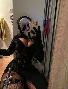 a woman in a costume is taking a selfie with her cell phone while wearing a mask