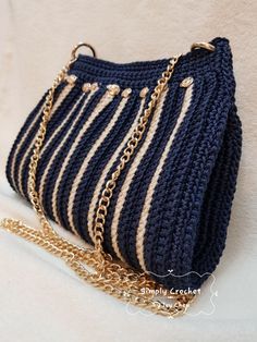 a crocheted purse with gold chains hanging from it's side on a white surface