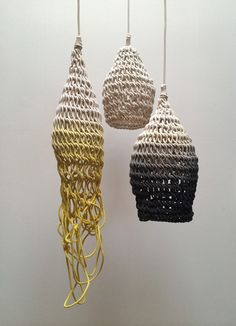 three crocheted pendants hanging from strings in various colors and sizes on a white wall