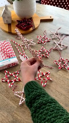 a person is making christmas decorations out of candy canes on a table with other items