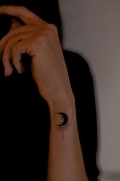 a woman's arm with a small sun and moon tattoo on her left wrist