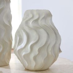 two white vases sitting on top of a table