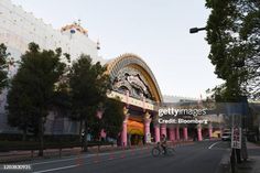 an empty street in front of a building with pink pillars and arches on the sides