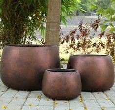 three large pots sitting on top of a stone floor