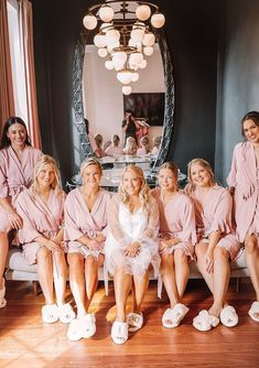 a group of women in pink robes sitting next to each other on a white couch