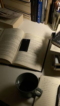 an open book sitting on top of a table next to a coffee cup and books