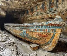 an old boat is sitting in the middle of a cave with paintings on it's walls