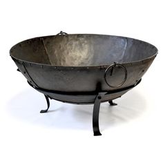 a large metal bowl sitting on top of a black stand with an iron ring in the middle